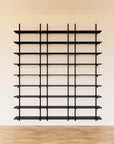 Modular media shelving unit with black shelves, black vertical posts, and three bays, shown with eight open shelf levels.