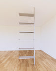 Floor-to-ceiling room divider shelving extension with lower storage cabinet with satin shelves and satin vertical post, one bay, 24-inch bay width, six open shelf levels, floor-to-ceiling supports.