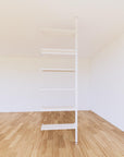 Floor-to-ceiling room divider shelving extension with lower storage cabinet with white shelves and white vertical post, one bay, 24-inch bay width, six open shelf levels, floor-to-ceiling supports.