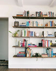 Modular shelving unit with Casting Light shelves, satin vertical posts, and one bay, shown with two open shelf levels styled in a room setting.