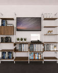 Four-bay media center shelving unit with white shelves and satin vertical posts, four bays, styled as an entertainment storage unit.