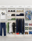 Retail display shelving unit with white shelves, white vertical posts, and four bays, plus signage, shown with open shelving.