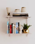 Modular shelving unit with white shelves, white vertical posts, and one bay, shown with two open shelf levels.
