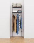 Closet storage system with black shelves and black vertical posts, plus hanger bars, shown with open shelving.