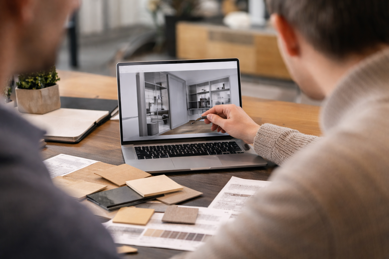 Two people looking at a laptop displaying interior design images in a kitchen setting.