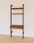 Desk shelving unit with wood-look shelves and black vertical posts, shown with desk surface and open shelf levels.