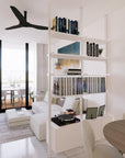 Floor-to-ceiling room divider shelving unit with lower storage cabinets with Casting Light shelves and satin vertical posts, 2 bays, 24-inch bay width, six open shelf levels, floor-to-ceiling supports, styled in a room setting with books and decor.