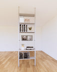 Floor-to-ceiling room divider shelving extension with lower storage cabinet with satin shelves and satin vertical post, one bay, 24-inch bay width, six open shelf levels, floor-to-ceiling supports.