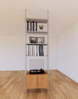 Floor-to-ceiling room divider shelving unit with lower storage cabinets with Tea for Two shelves and satin vertical posts, one bay, 24-inch bay width, six open shelf levels, floor-to-ceiling supports.