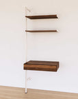 Desk shelving extension with wood-look shelves and white vertical post, shown with desk surface and open shelf levels.