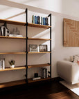 Wood shelf modular shelving unit with Casting Light shelves and black vertical posts, one bay, styled in a modern room.