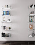 Modular shelving unit with white shelves, satin vertical posts, and one bay, shown with three open shelf levels styled in a room setting.