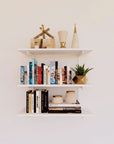 Modular shelving unit with black shelves, black vertical posts, and one bay, shown with three open shelf levels styled in a room setting.