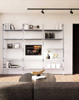 Modular media shelving unit with white shelves and white vertical posts, one bay, styled as an entertainment storage unit.