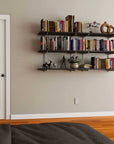 Modular shelving unit with black shelves, black vertical posts, and one bay, shown with two open shelf levels styled in a room setting.