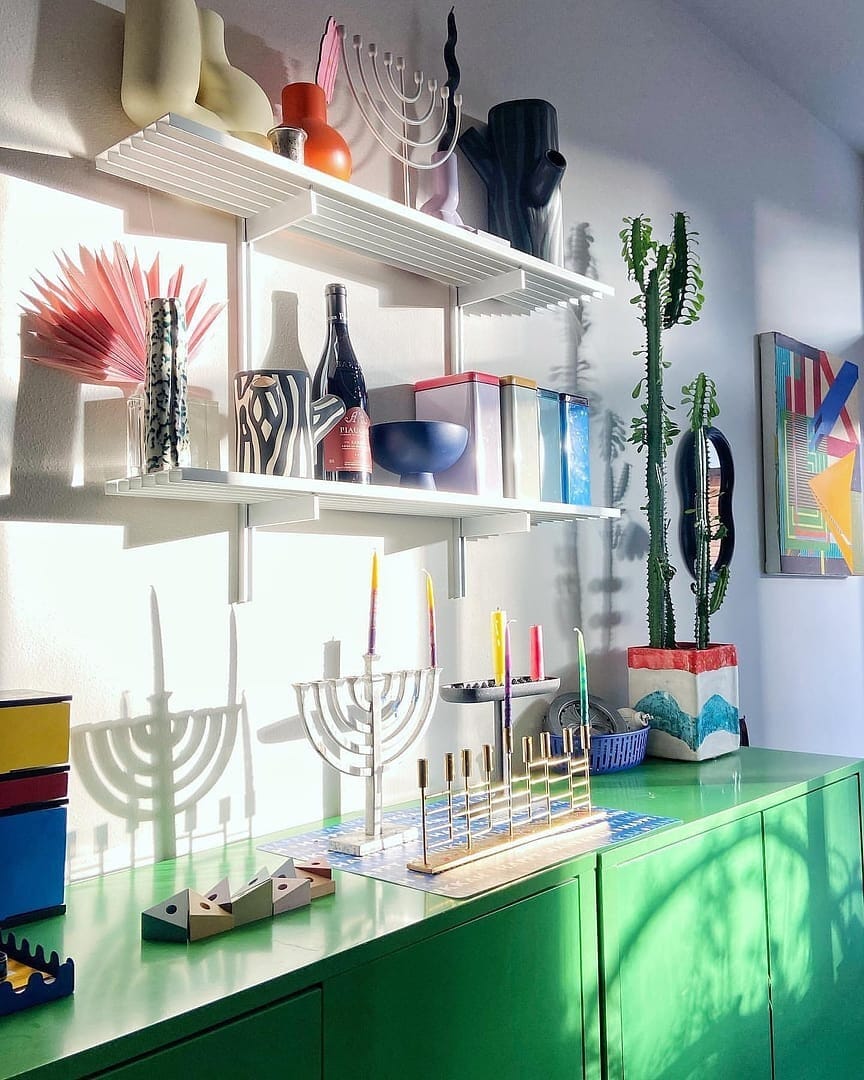 Modular shelving unit with satin shelves, satin vertical posts, and one bay, shown with two open shelf levels styled in a room setting.